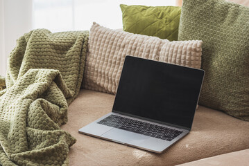 Laptop on Cozy Sofa with Textured Pillows and Blanket. Relaxed Home Workspace