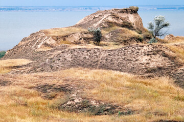 Dry steppe hills overlooking wide river under hazy sky in summer