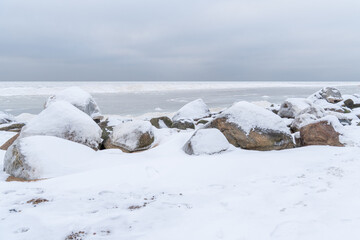 Snow-Covered Coastal Boulders by Frozen Baltic Sea Under Overcast Winter Sky