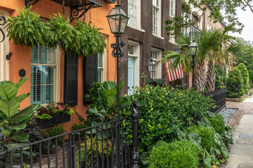 Obraz premium Charleston, South Carolina, USA - May 27, 2025: Colorful Historic Homes with Gas Lamps and Lush Gardens on Adgers Wharf street in Historic Charleston