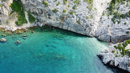 ​Aerial view of a steep limestone cliff coastline with crystal clear turquoise water. Rugged Mediterranean sea shore landscape.