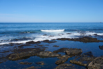 The waves crash against the rocks on the coast.