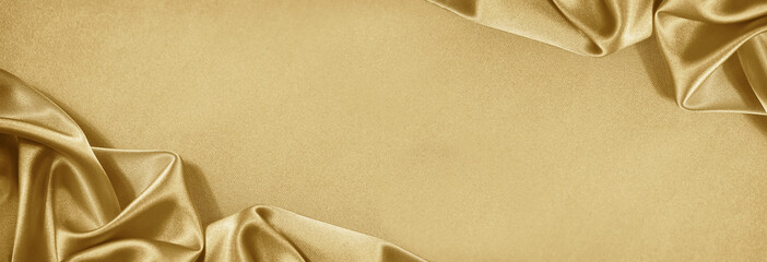 Light soft golden silk satin. Shiny silky fabric. Wavy folds. Draped. Elegant luxury background. Empty blank space template design ad. Christmas festive birthday. Flat lay, top view table.Wide banner.