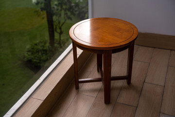 A round table sits on beige tiles next to a glass window