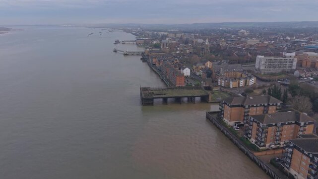 Gravesend town by the river Thames aerial view. Flying above the river Thames towards historic Gravesend pier. Wide river with commuter town on the outskirts of London, UK.