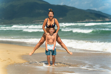 A mother enjoys jumping while on vacation with her child on the beach and sea
