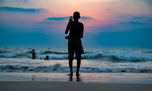 Sunset at Colva Goa beach in South India, silhouette of people, tropical west coast, Arabian Sea in Asia, vacation destination