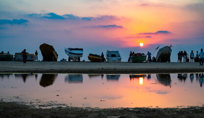 Sunset at Colva Goa beach in South India, silhouette of boats and people, tropical west coast, Arabian Sea in Asia, vacation destination