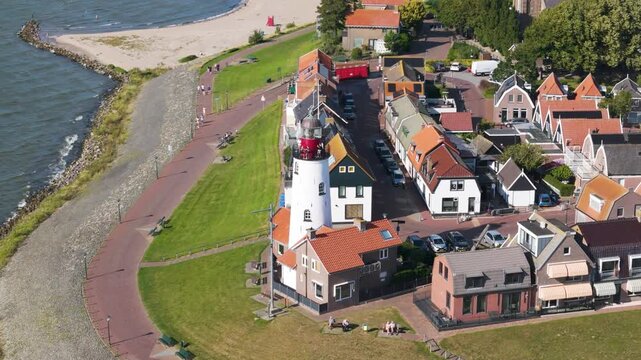 red roofed homes green lawn surround iconic lighthouse by rocky coastline high seaside promenade urk netherlands angle shot view red-roofed flevoland high-angle landmark tourism 