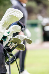 A man is walking with a golf bag and a few golf clubs