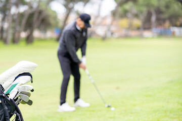 A man is playing golf and there are several golf clubs