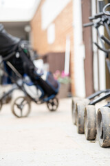 A row of golf carts are lined up on a sidewalk, with a blurry bag on the background