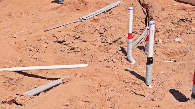 Workers are setting up plumbing electrical lines at construction site for building foundations.