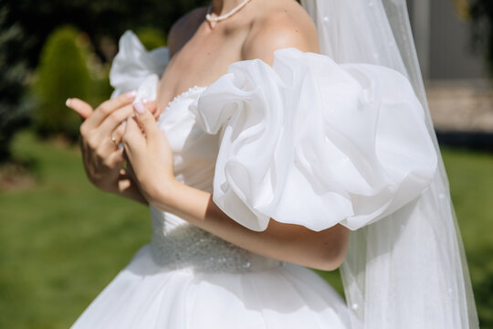 Elegant charming gentle bride in a white dress with puffy sleeves on a park background