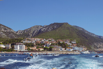 Fototapeta premium Veduta di Cala Gonone dalla barca. Mare e paesaggio collinare con paese sullo sfondo. Estate.
