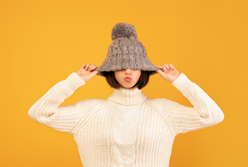 Pretty young woman pulling down woollen hat, showing kissing lips, fooling and posing to camera...