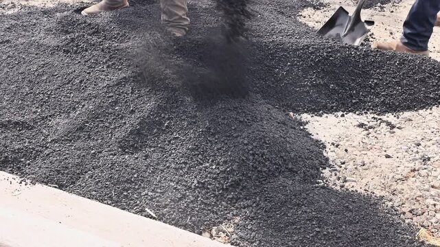 October 14 2025 New York USA Several workers use shovels to spread fresh asphalt across highway maintenance in residential area under road construction