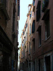 Fototapeta premium Narrow alleyway in Venice with charming pastel buildings and sunlight
