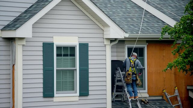 A worker removes old metal siding panels from the outside walls of the private house