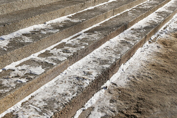 Slippery concrete steps in winter. Sand spread for safety. Icy pedestrian stairs detail. Dangerous...