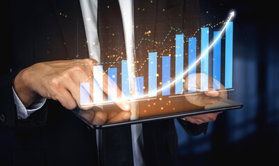 A business professional engaging with a digital tablet to analyze data trends through a modern graph interface. The scene captures the essence of growth in a contemporary office setting. Impute