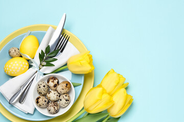 Easter celebration. Festive table setting with tulip flowers, green leaves, painted and quail eggs...