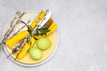 Festive table setting with Easter eggs and willow branches on light background, top view. Space for...