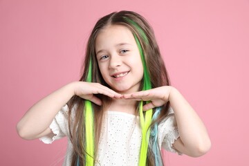 Cute girl with bright clip-in hair extensions on pink background