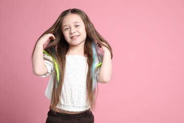 Cute girl with bright clip-in hair extensions on pink background. Space for text