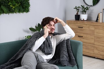 Fototapeta premium Man talking over phone on sofa at home
