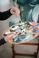 Obraz premium Artist holds a palette full of paint while creating a colorful artwork in a studio during daylight hours
