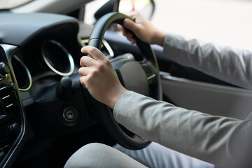 Naklejka premium Driver work, travel and road to office in new normal car in city. Ad of transport, rent and sale. Young man in suit is driving new auto with hands on steering wheel, cropped, close up, empty space