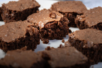 Close-up of a chocolate brownie cut into pieces on a white plate.