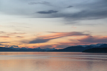 orange sunset on the shores of the lake with mountains in the background
