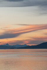 orange sunset on the shores of the lake with mountains in the background