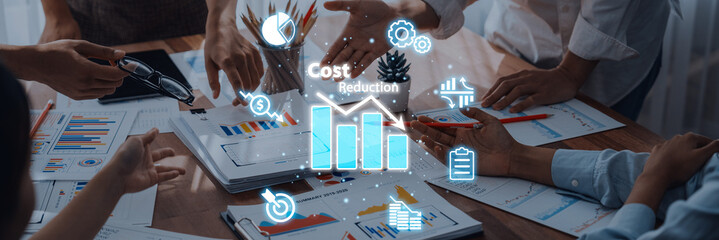 A collaborative business meeting in a modern office focusing on cost reduction strategies. Professionals discuss data and charts while sharing insights to enhance business performance. Trope
