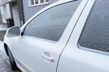 Winter's icy touch blankets a car, its windows veiled in a delicate frost. The world outside blurs behind a crystalline curtain of cold beauty.