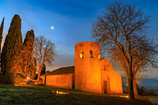 The Romanesque facade and stone bell tower of the Pieve dei Santi Vito e Modesto a Corsignano, an ancient church located in the Val d'Orcia region of Tuscany