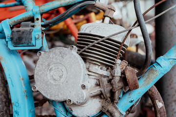 Close-up view of a vintage motorcycle engine with a blue frame, showcasing rust and wear,...