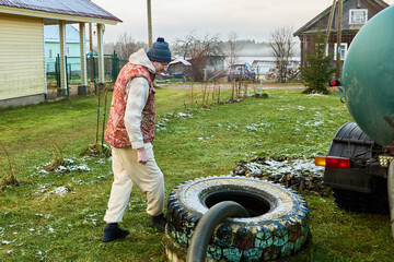 Pumping sewage from septic pit using sewage vacuum truck hose as sanitation worker operates cesspool cleaner ensuring controlled removal of waste.