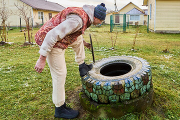 Checking septic tank content during sanitation service as sanitation worker observes sewage and wastewater level inside concrete ring for routine waste management.
