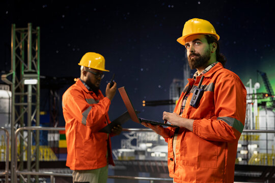 Industrial drilling rig engineering team inspecting equipment integrity using laptop. Offshore sea platform employees performing preventative maintenance checks on machinery to ensure safety