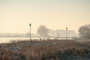Morning glow over De Ijssel river with red crib beacons guiding gentle waters near Kampen and Zwolle