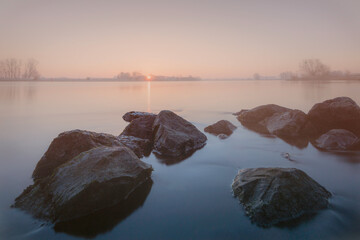 Morning light dances over the flowing river IJssel in the Netherlands at sunrise