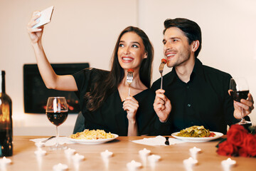 Capturing Moments. Beautiful lovely excited young couple taking selfie while sitting at table and...