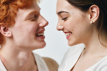 Naklejka premium Young man and woman smiling closely with eyes closed in intimate moment, showing affection and happiness on light background. Positive emotion and connection between couple.