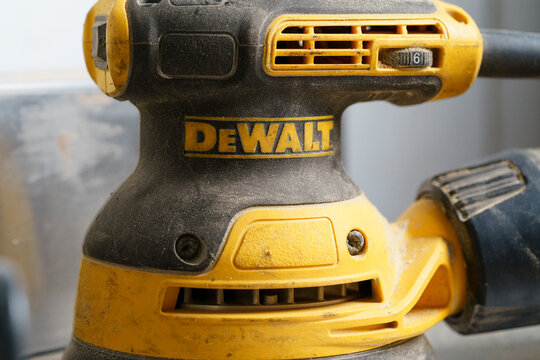 Close up of yellow DeWalt orbital sander power tool with dust on workshop surface