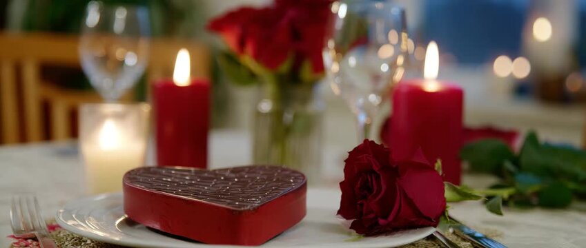 A beautifully arranged romantic dining setup with roses, chocolates.