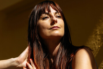 Fototapeta premium Confident young caucasian female with long brown hair in sunlight