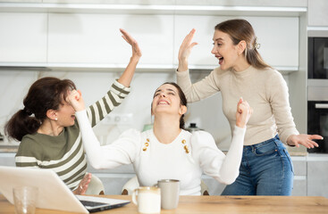 Fototapeta premium Gleeful ladies in their middle years exulting over big premium in internet while sitting in their house
